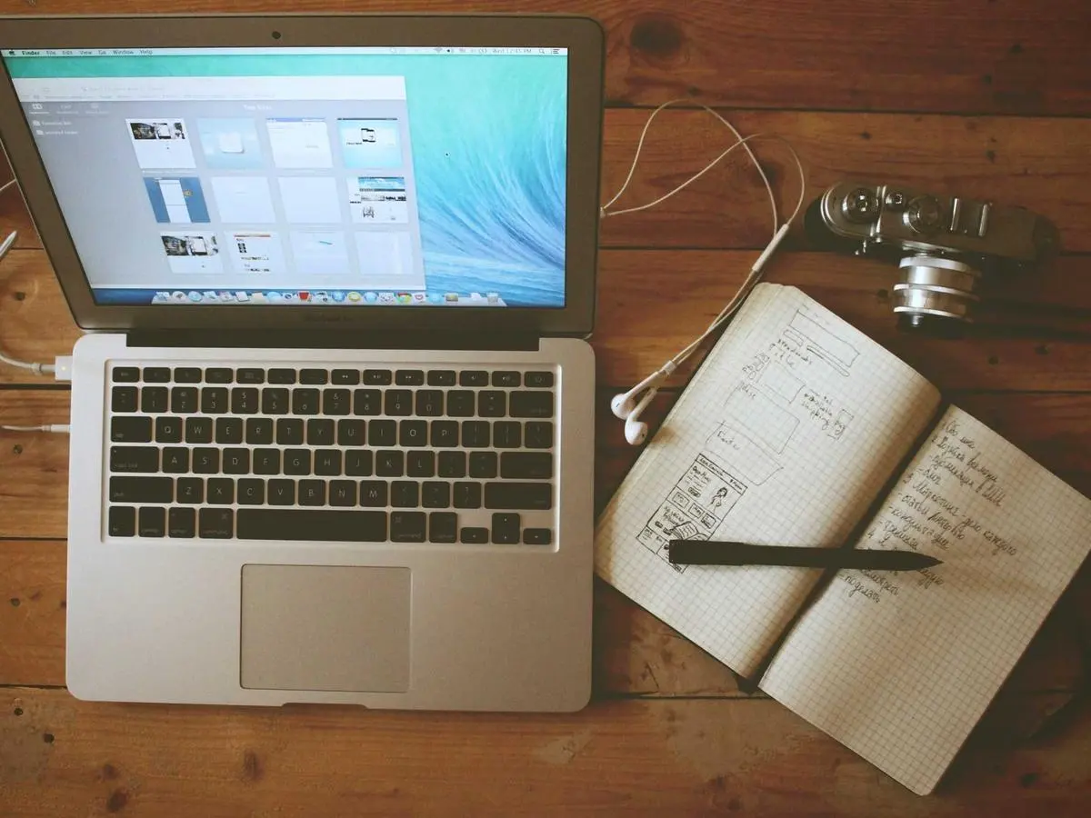 Laptop and a notebook of interface sketches on a desk during web development work