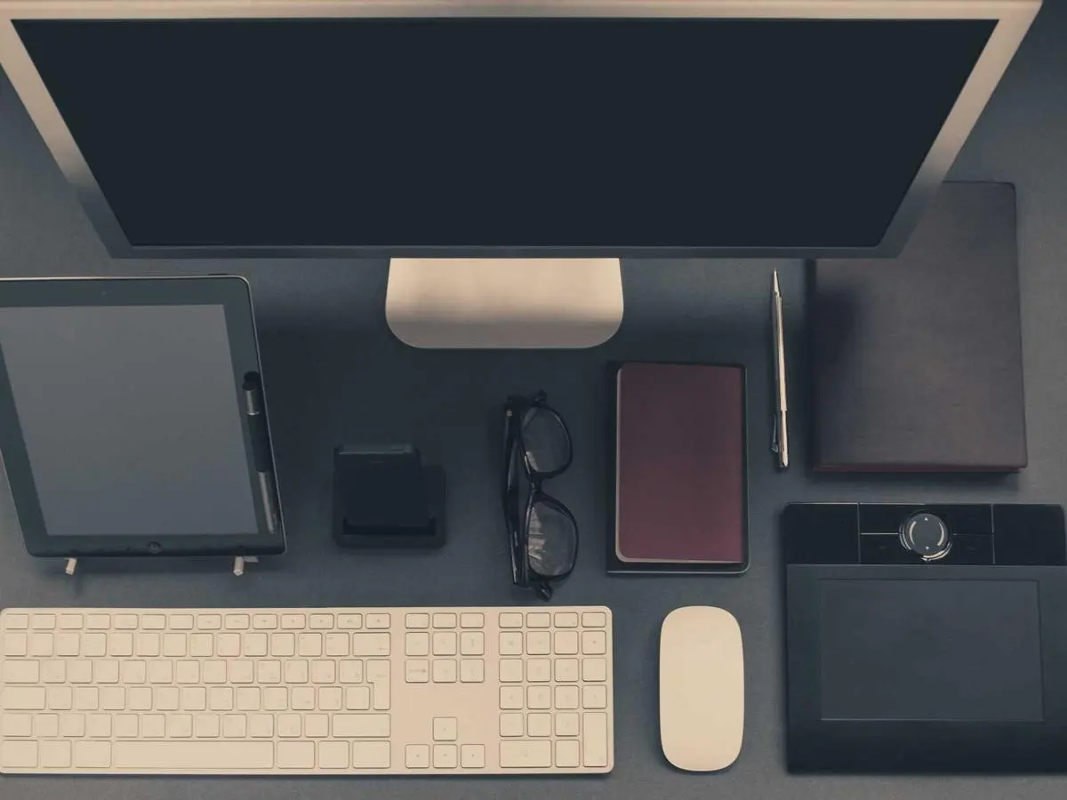 Desk with a monitor, keyboard, tablet and office equipment seen from above